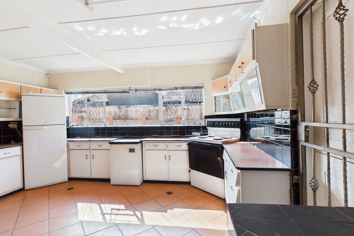 A dated kitchen featuring original cabinetry, tiled backsplash, and tiled flooring, offering significant potential for a modern renovation and layout update.