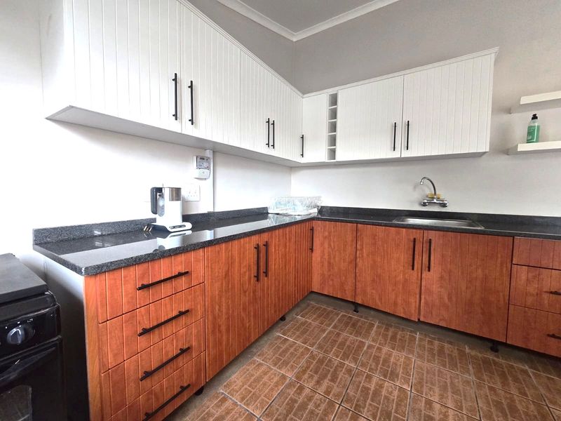 A well-maintained kitchen featuring contrasting white upper and wood-grain lower cabinetry, granite countertops, and durable tiled flooring.