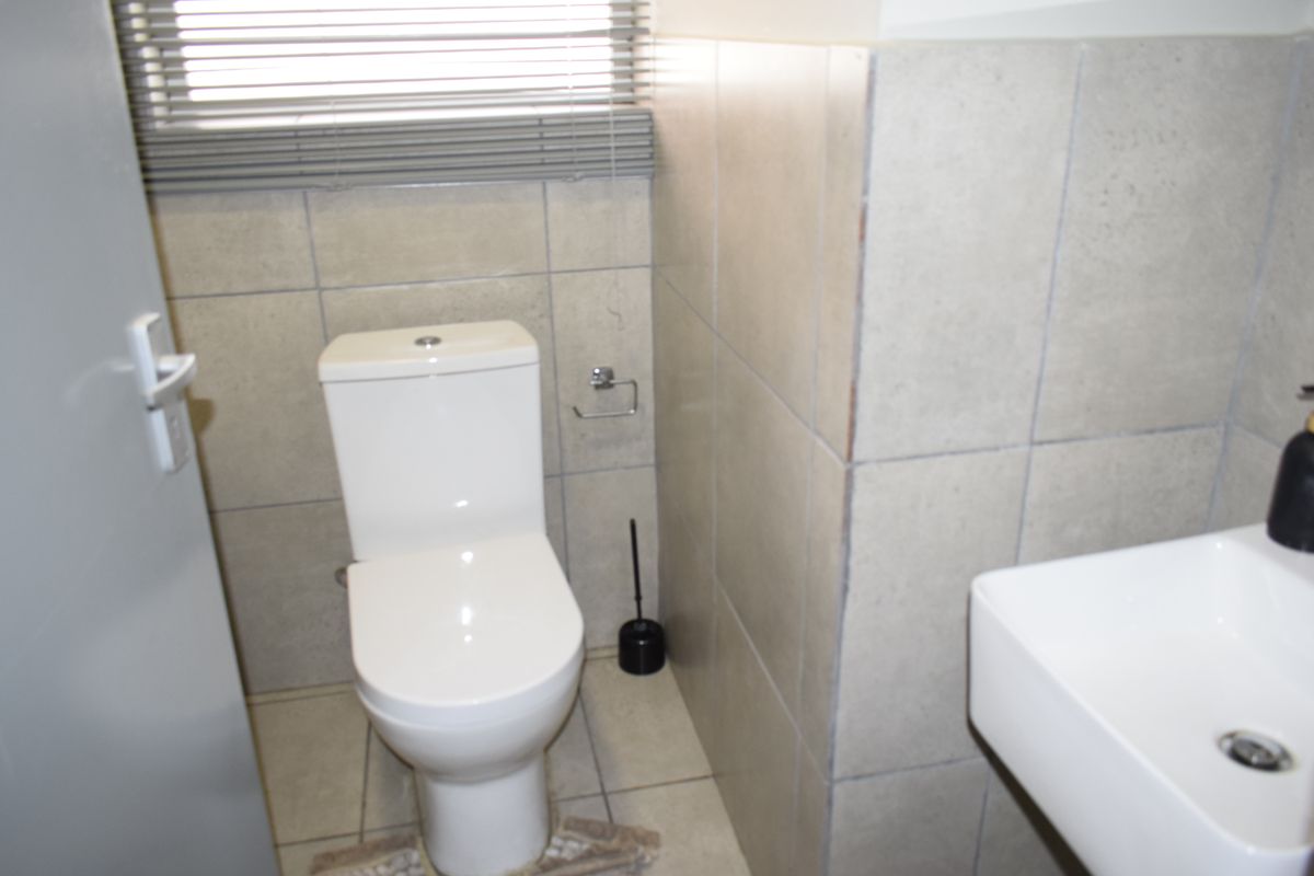 A compact guest bathroom featuring a modern toilet, wall-mounted basin, and neutral tiled finishes throughout.