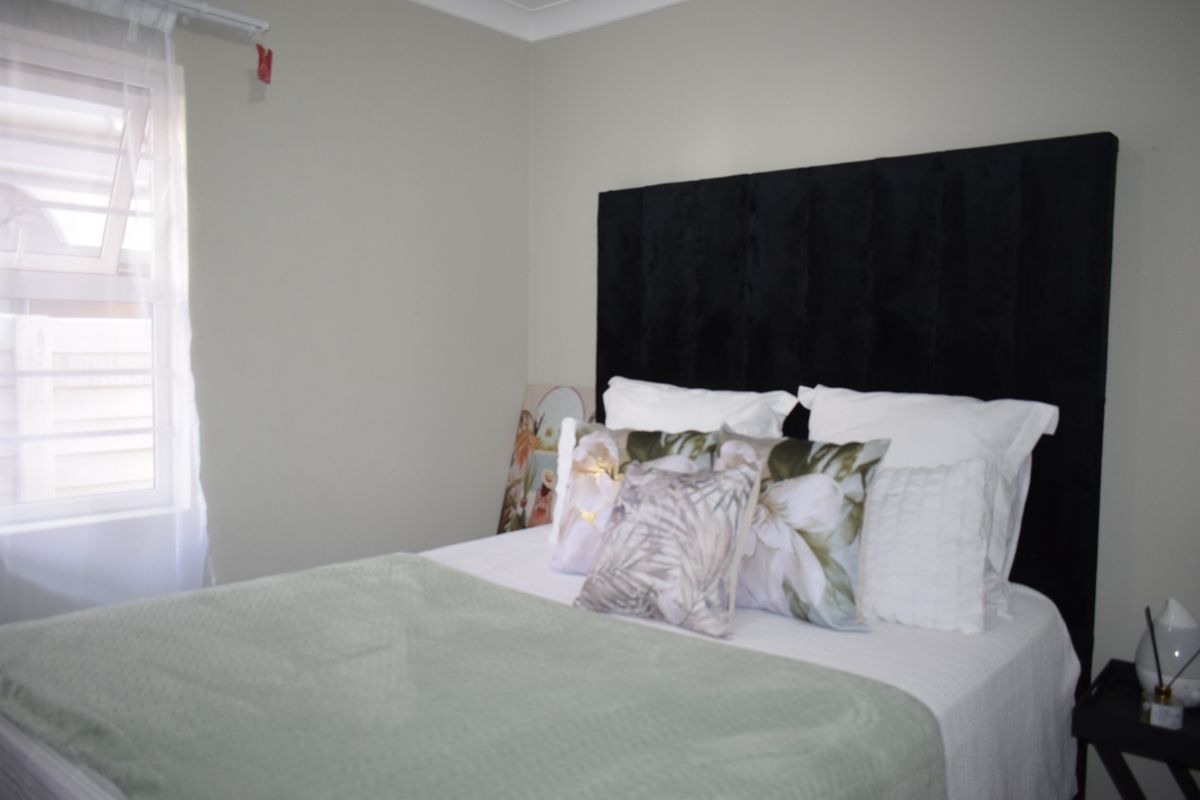 A well-maintained bedroom featuring neutral wall tones and a functional louvre window for natural ventilation.