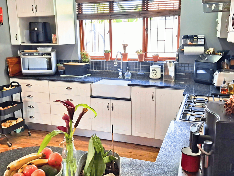 A functional kitchen featuring white cabinetry, a farmhouse sink, dark countertops, and a gas hob, providing a practical workspace with ample storage.