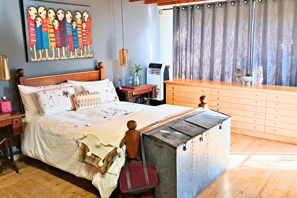 A well-maintained bedroom featuring warm timber flooring, built-in storage cabinetry, and modern pendant lighting, creating a comfortable and functional living space.