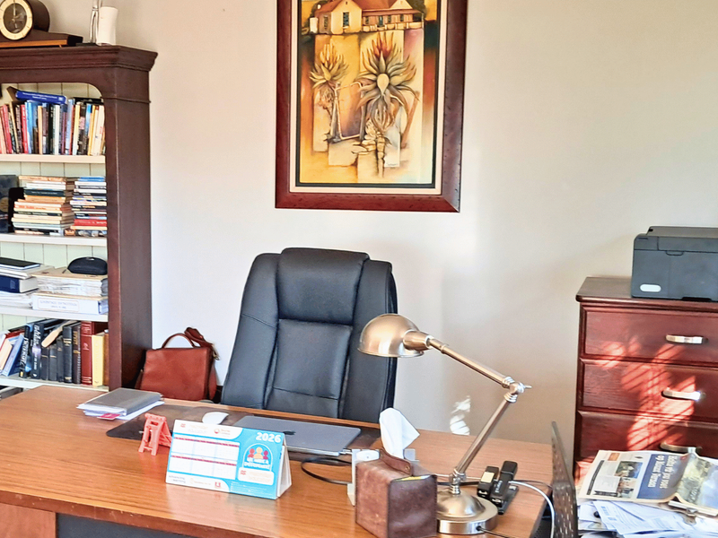 A functional home office space featuring a built-in wooden shelving unit and ample desk workspace.