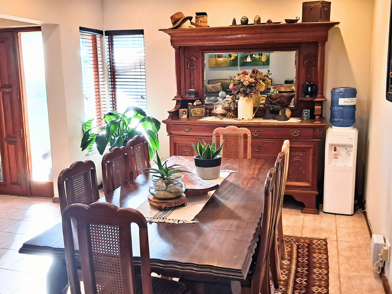 A dining room featuring tiled flooring, a timber entrance door, and natural light through venetian blinds, providing a functional space for family meals.