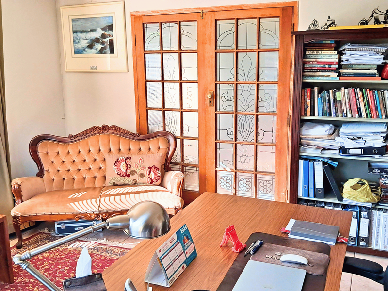 A home office space featuring classic leaded glass double doors and natural light from a side window.