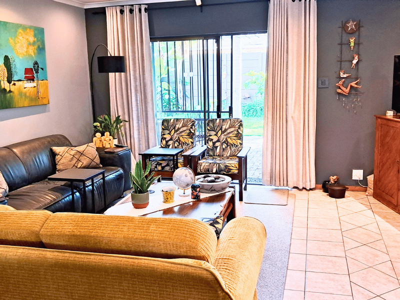 A comfortable living room featuring tiled flooring and a sliding glass door with security gate providing access to the outdoor area.