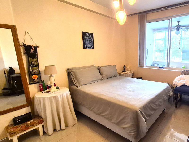 A bedroom featuring tiled flooring, a large sliding window providing natural light, and modern pendant lighting fixtures.