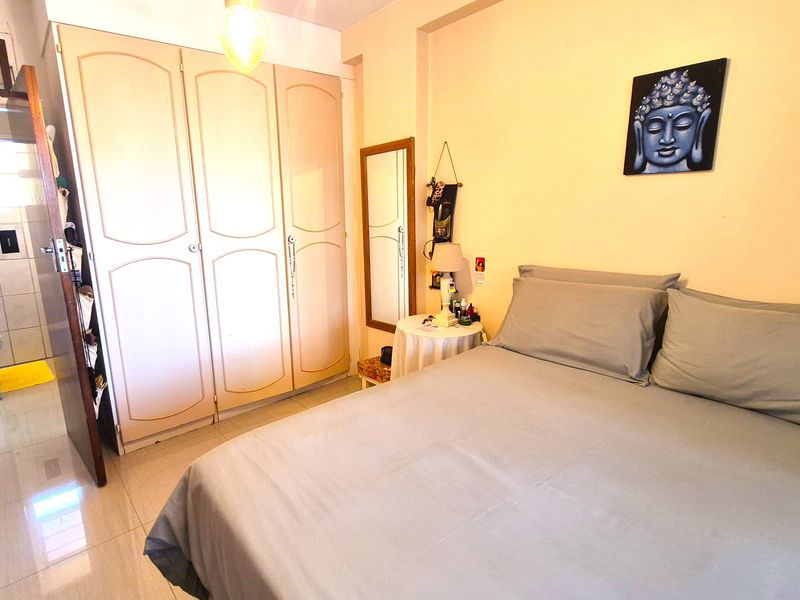 A bedroom featuring built-in wardrobes, tiled flooring, and direct access to an en-suite bathroom.