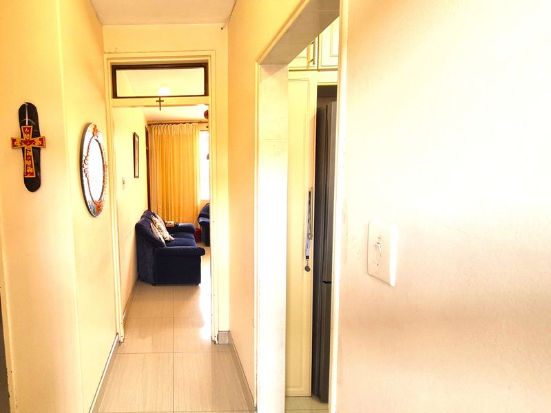 A functional hallway connecting living spaces, featuring tiled flooring and access to adjacent rooms with built-in storage cabinetry.