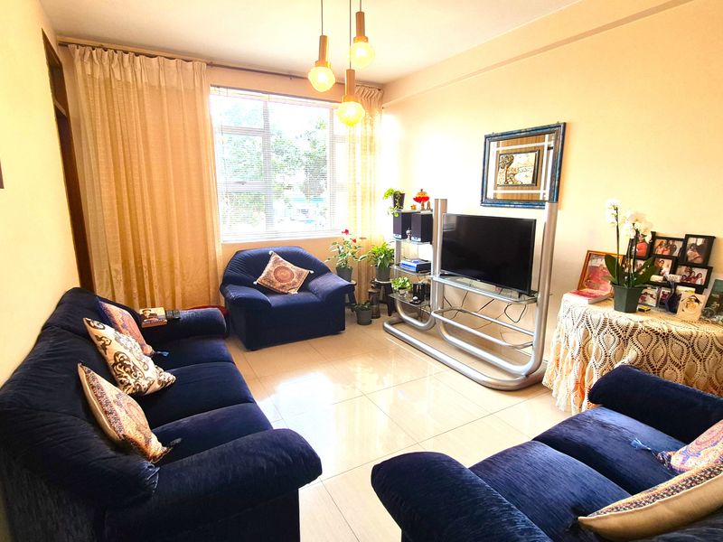 A comfortable living room featuring tiled flooring, a large window for natural light, and modern pendant lighting.