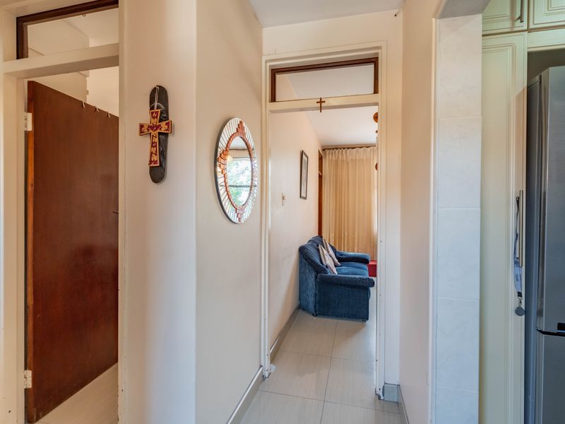 A functional hallway connecting living spaces, featuring tiled flooring and traditional door frames with transom windows.