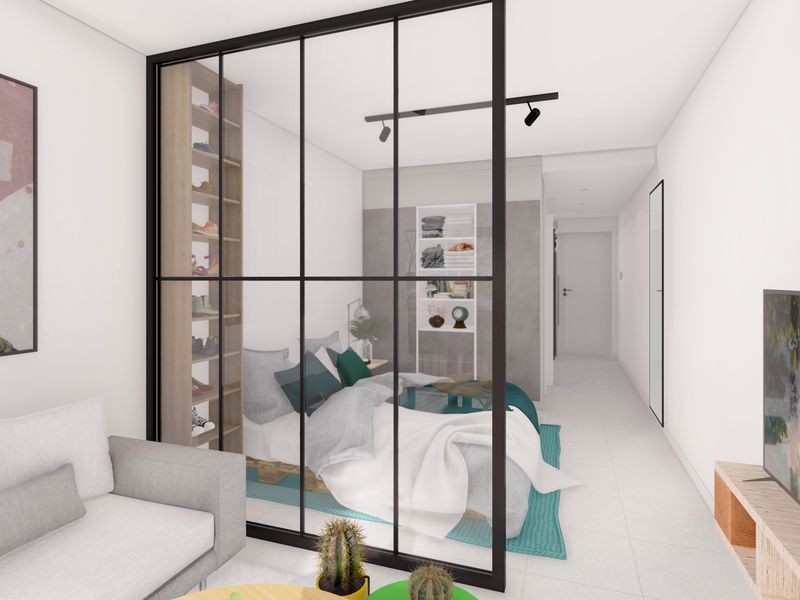Modern open-plan apartment interior featuring a sleek black metal and glass partition separating the living area from the bedroom space.