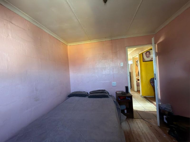 A bedroom featuring exposed blockwork walls, timber flooring, and a coved ceiling, requiring cosmetic updates to improve the overall finish and appeal.