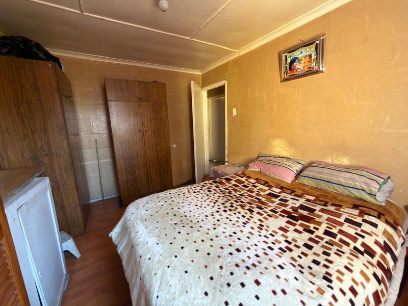 A bedroom featuring laminate flooring, built-in cupboards, and coved ceilings, requiring cosmetic updates to improve the overall aesthetic and condition.