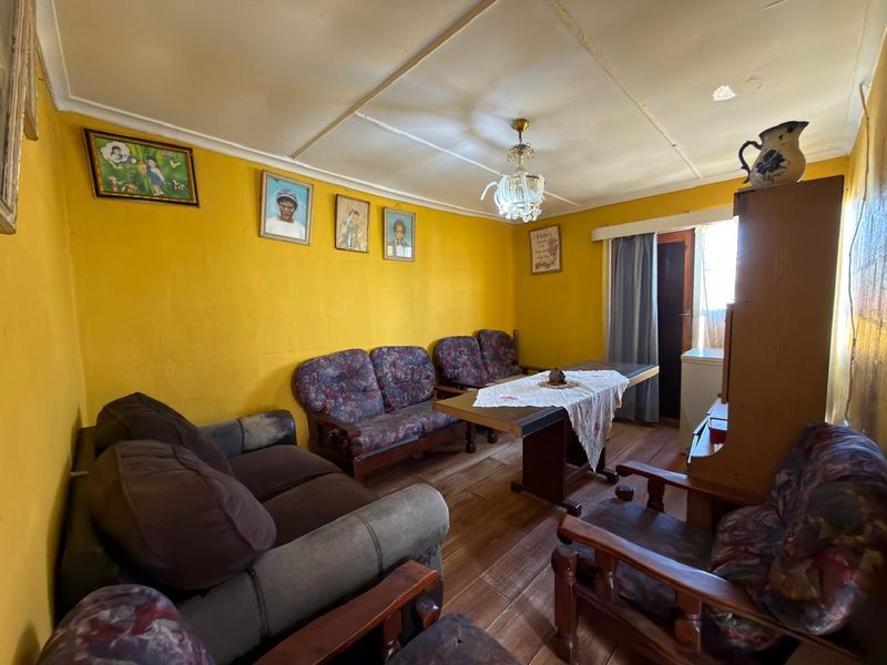 A living room featuring tiled flooring and ceiling panels, requiring cosmetic updates to modernize the space.