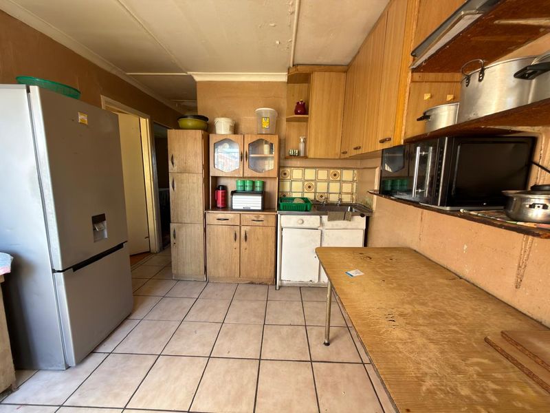 A dated kitchen featuring laminate cabinetry, tiled flooring, and a tiled backsplash, offering significant potential for modernization and renovation.
