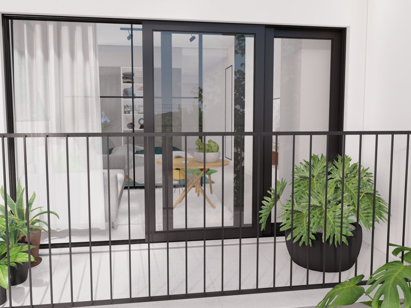 A modern balcony featuring a sleek black metal balustrade and large sliding glass doors providing access to the interior living space.