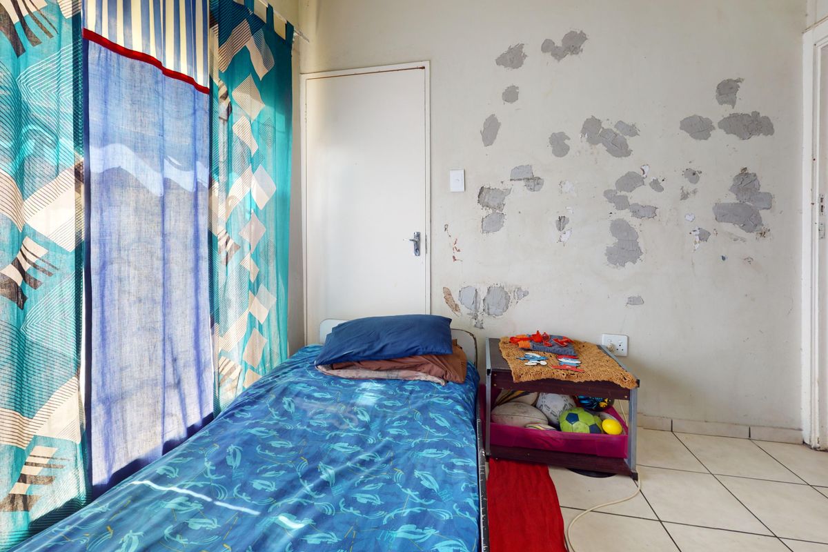 A bedroom featuring tiled flooring and significant wall surface damage requiring repair and repainting.
