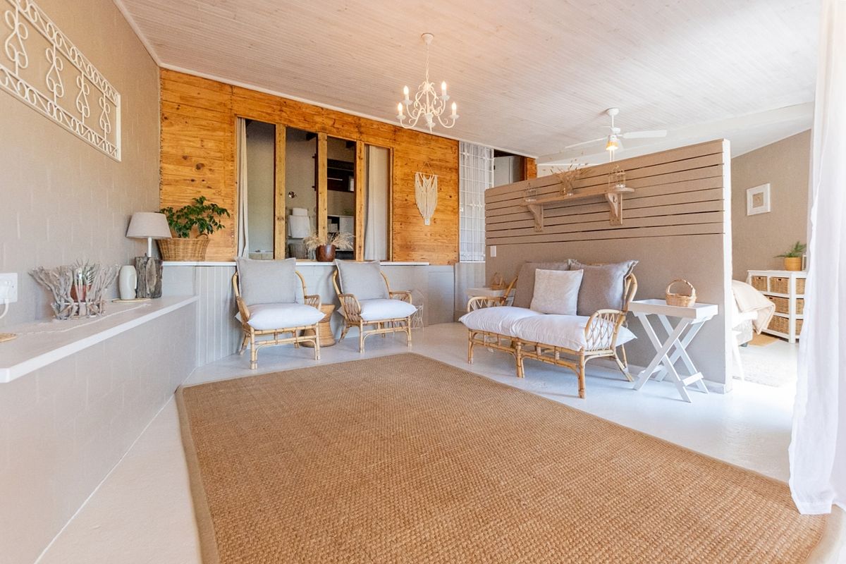 A bright living area featuring timber wall paneling, a decorative partition wall, and a ceiling fan, creating a warm and inviting atmosphere.
