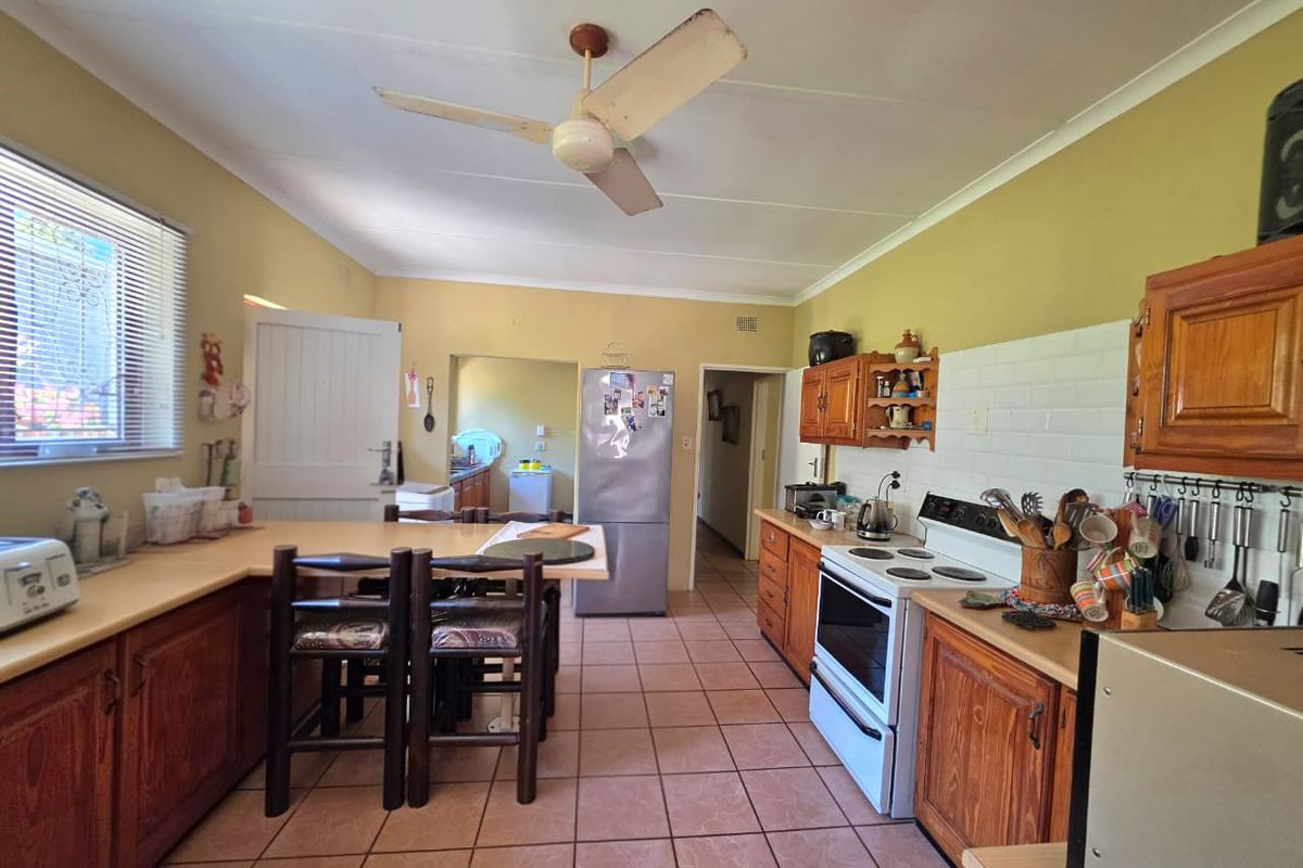 A functional kitchen featuring wooden cabinetry, tiled flooring, a ceiling fan, and a tiled backsplash, offering a traditional layout with ample storage space.