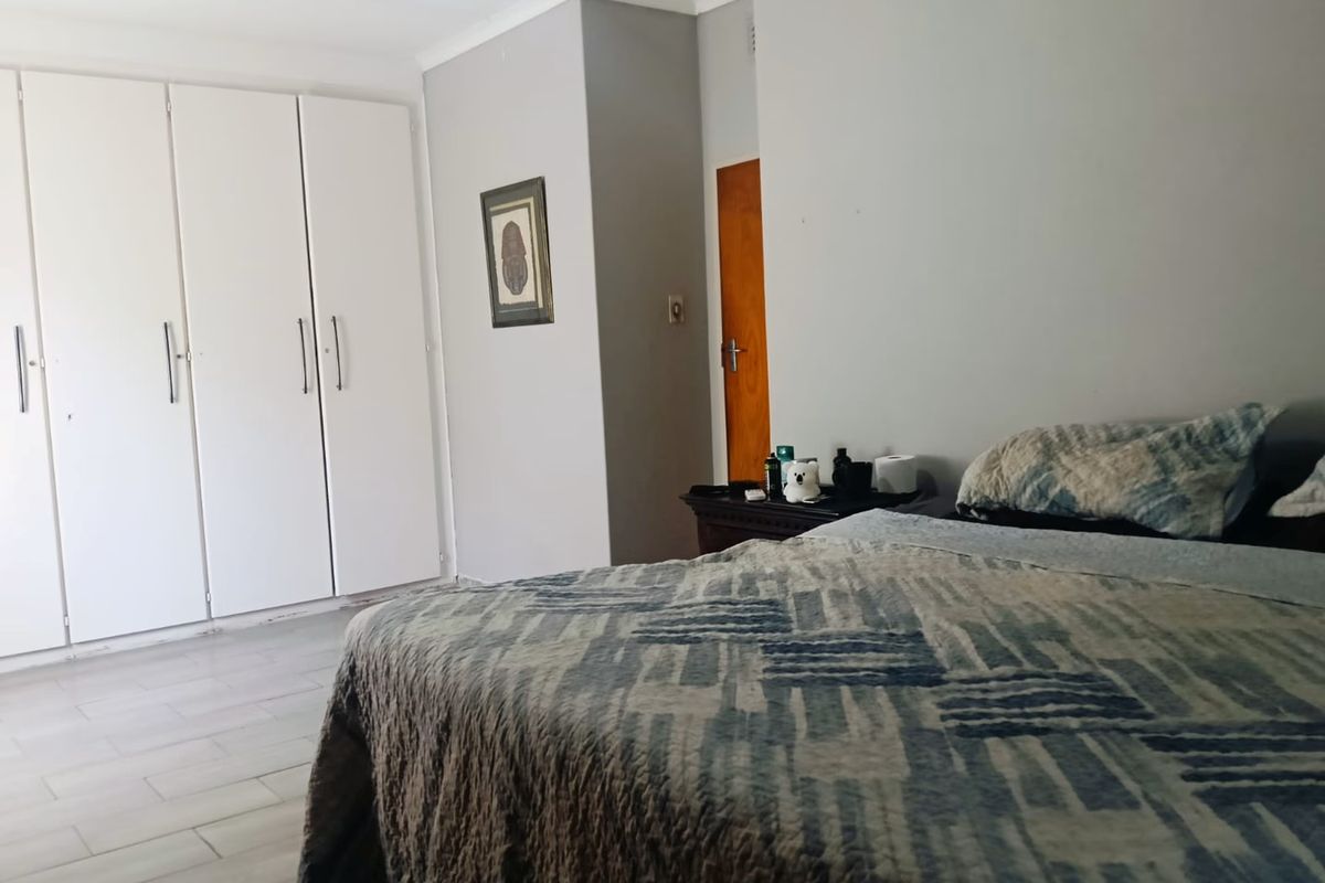 A bedroom featuring built-in cupboards and tiled flooring, offering a functional and neutral space.