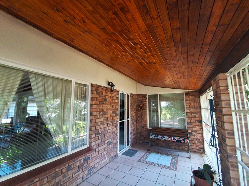 A covered patio area featuring a warm timber-clad ceiling, face brick walls, and tiled flooring, providing a sheltered outdoor space.