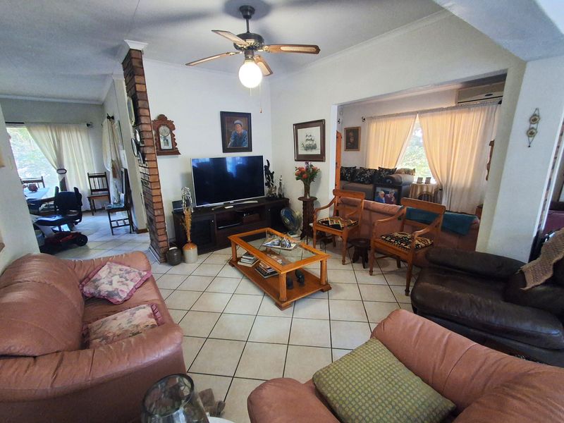 Spacious open-plan living area featuring tiled flooring, an exposed brick feature pillar, and a ceiling fan, creating a comfortable and connected family space.