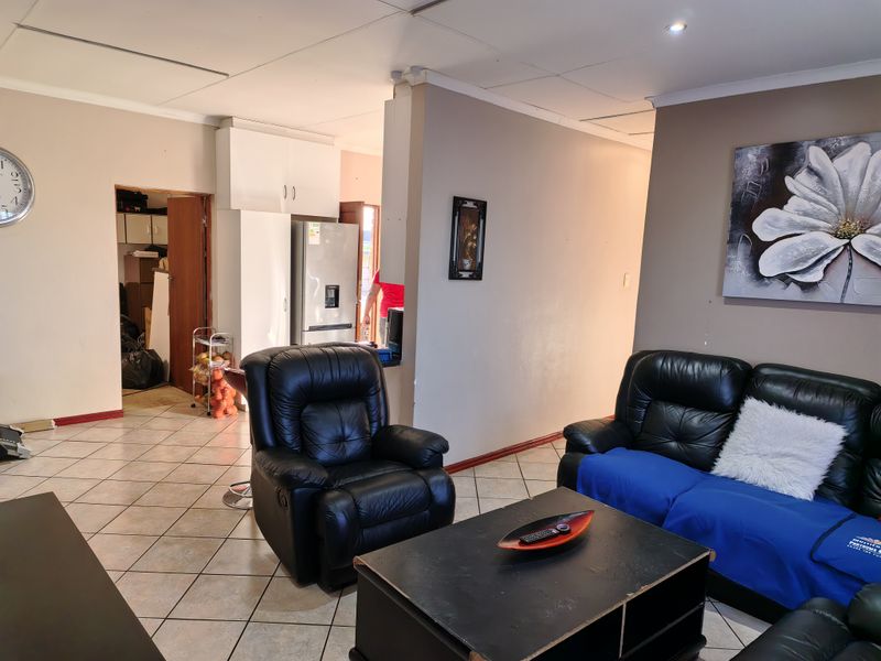 Open plan living area featuring tiled flooring and recessed lighting, connecting to a kitchen and utility space with built-in cabinetry.