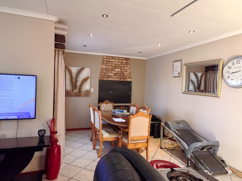 A living area featuring a built-in brick fireplace, recessed downlighting, and tiled flooring, providing a functional space for dining or relaxation.