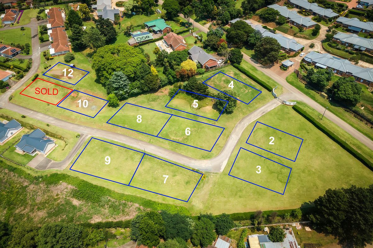 Aerial view of a residential townhouse development site featuring multiple demarcated plots and paved access roads within a landscaped estate setting.