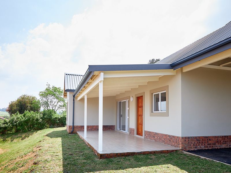 A well-maintained covered patio featuring tiled flooring, brick accents, and direct access to the interior through a sliding glass door.