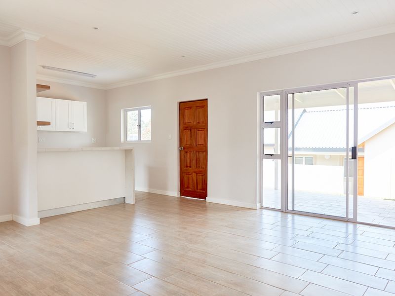Bright open-plan living area featuring tiled floors, a breakfast bar, and sliding glass doors leading to an outdoor patio space.