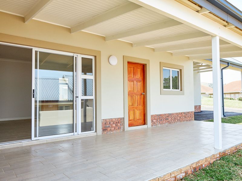 A clean, covered patio area featuring tiled flooring, a sliding glass door, and a solid timber door, providing a seamless transition to the outdoors.