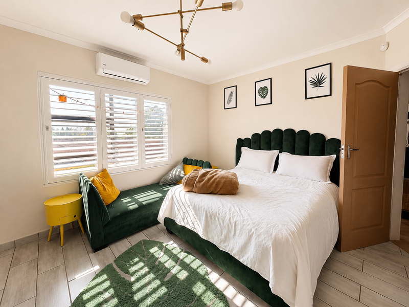 A well-maintained bedroom featuring tiled flooring, plantation shutters, and a wall-mounted split-system air conditioner.