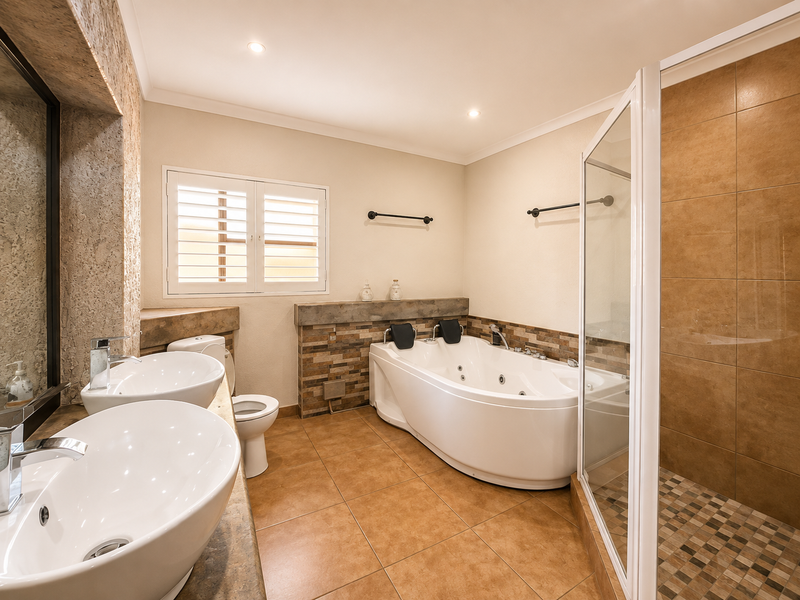 Spacious bathroom featuring a double vanity with vessel sinks, a built-in jetted bathtub, and a separate walk-in shower with tiled finishes.