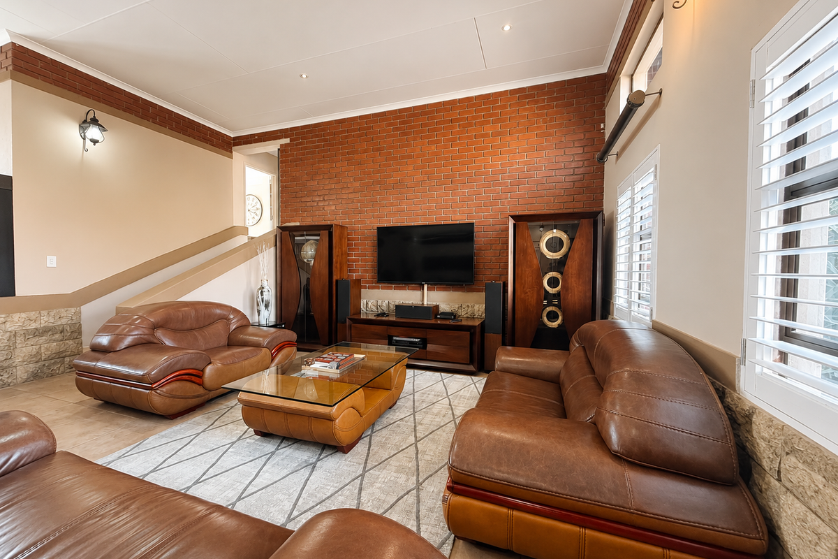 Spacious living room featuring an exposed brick feature wall, tiled flooring, and plantation shutters, creating a warm and inviting atmosphere.