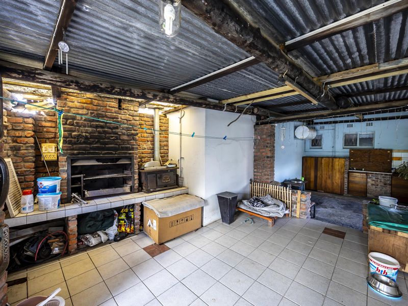 Covered outdoor entertainment area featuring a built-in braai, exposed brick walls, and corrugated iron roofing, offering potential for a rustic renovation.