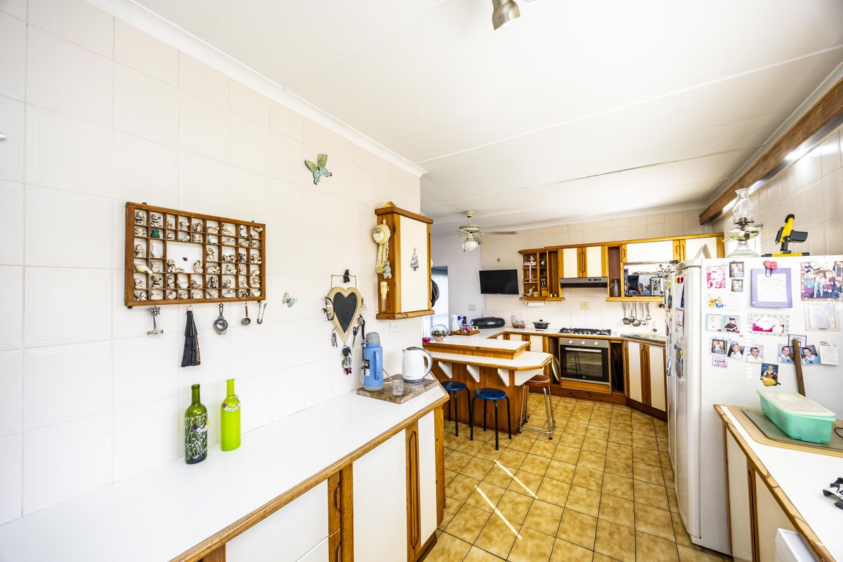 A functional kitchen featuring tiled flooring, built-in cabinetry, a gas hob, oven, extractor fan, and a breakfast bar area.