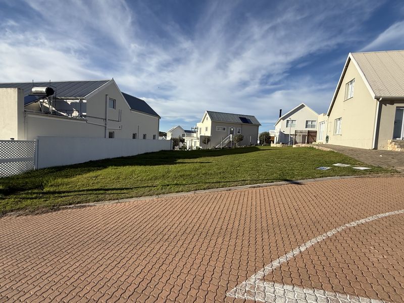 A vacant residential plot featuring a well-maintained lawn and paved driveway access, situated within a developed neighborhood setting.