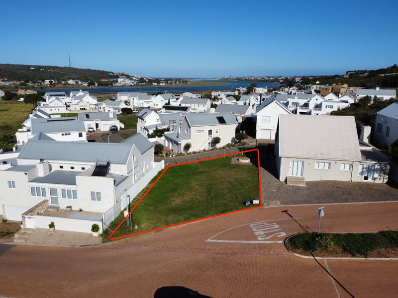 An aerial view of a vacant residential plot in a coastal estate, highlighting the property boundaries and surrounding neighborhood context.