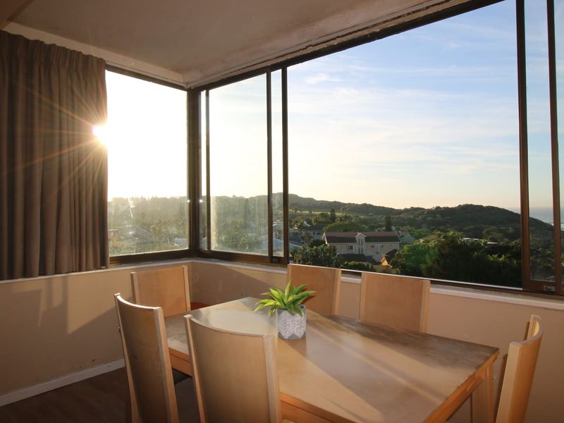 Dining area featuring expansive wrap-around windows with scenic coastal and landscape views, providing abundant natural light and a bright, airy atmosphere.