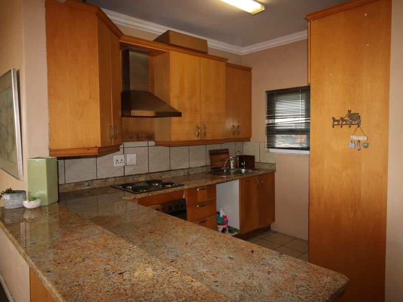 A functional kitchen featuring granite countertops, wooden cabinetry, a built-in oven with extractor fan, and a tiled backsplash.