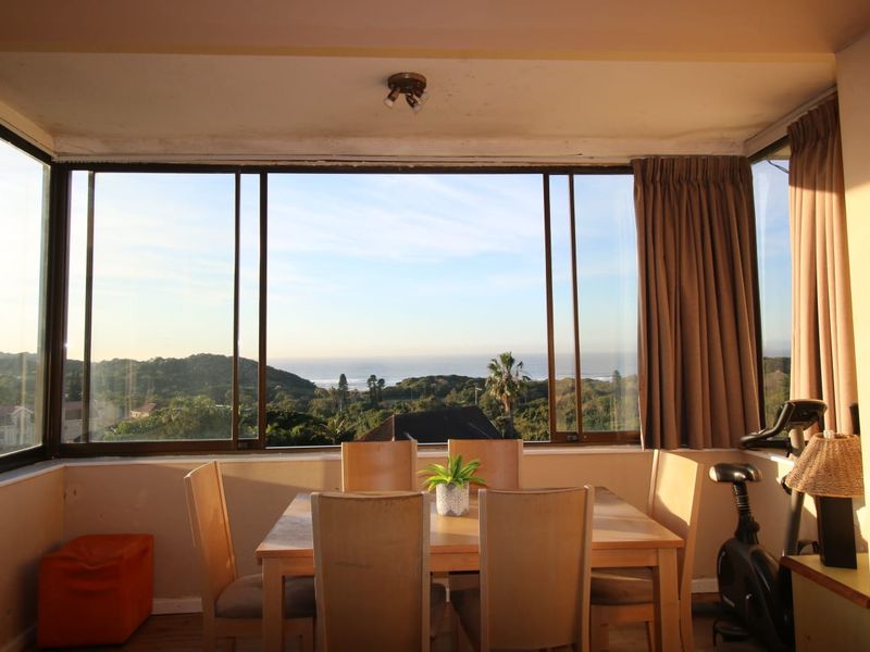 Living area featuring expansive sliding windows with panoramic coastal and landscape views, providing abundant natural light.