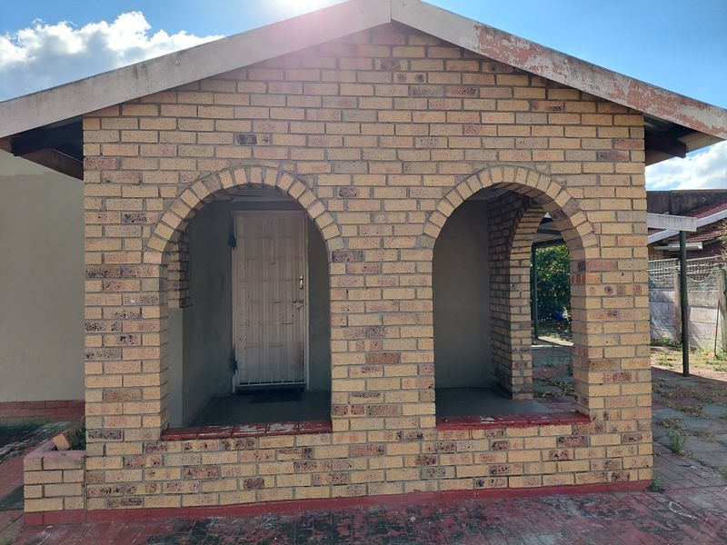 Front facade featuring a face brick exterior with arched openings, a security gate entrance, and a paved patio area.