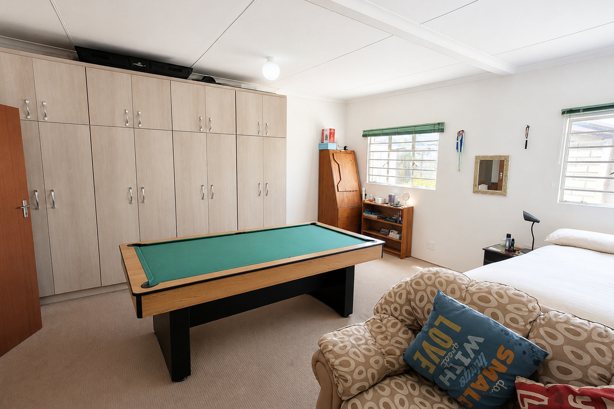 Spacious bedroom featuring extensive built-in cupboard storage, neutral carpeting, and natural light through multiple windows.