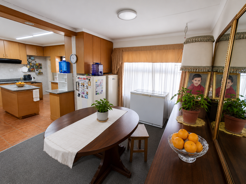 Open plan kitchen and dining area featuring wooden cabinetry, a central kitchen island, and a combination of tiled and carpeted flooring.