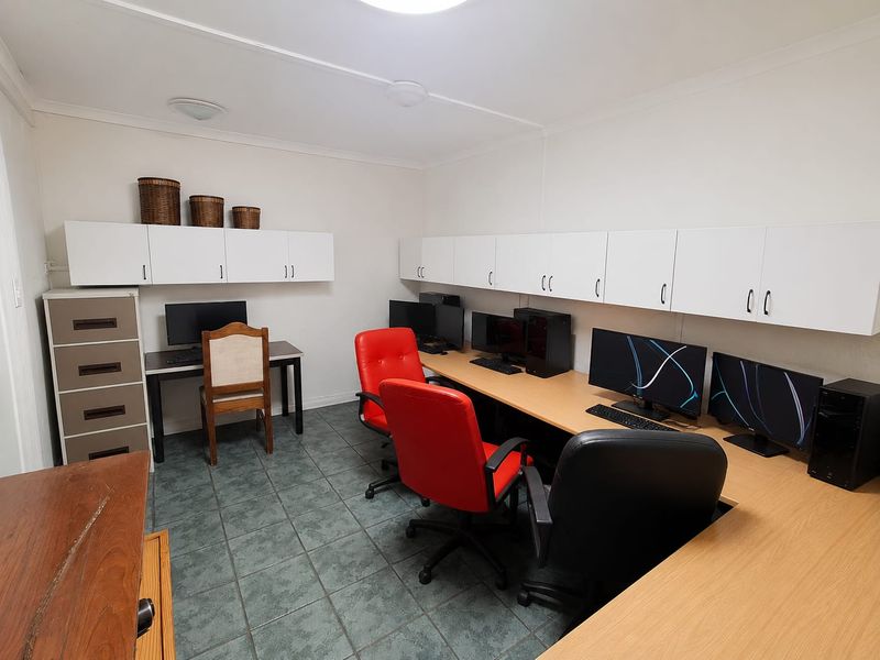 A functional home office space featuring extensive built-in wall cabinetry and durable tiled flooring, providing ample storage and workspace.