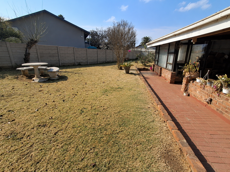 Rear garden featuring a brick-paved patio area, sliding glass doors, and a secure precast concrete boundary wall.
