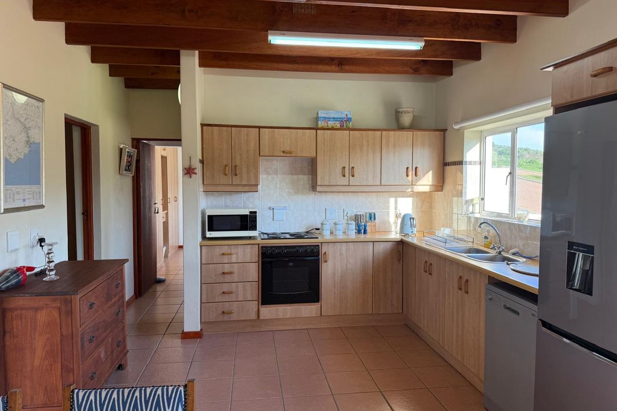 Functional kitchen featuring laminate cabinetry, exposed timber ceiling beams, tiled flooring, and a built-in oven with gas hob.