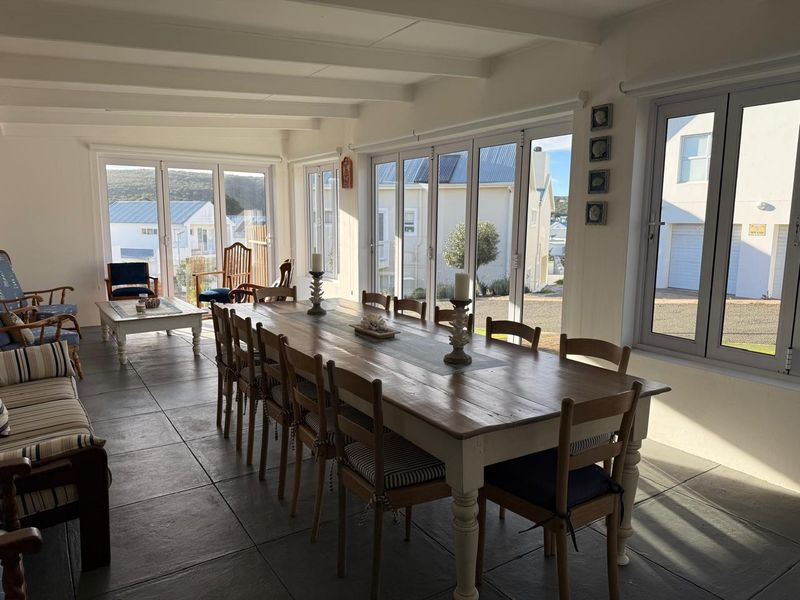 Spacious dining area featuring large bi-fold doors, tiled flooring, and exposed beam ceilings, offering abundant natural light and seamless access to the outdoors.